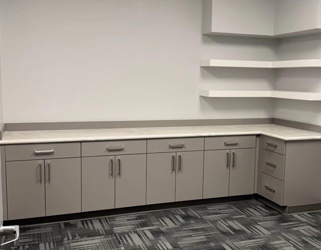 Commercial break room with cabinet run, quartz counter and white floating corner shelves