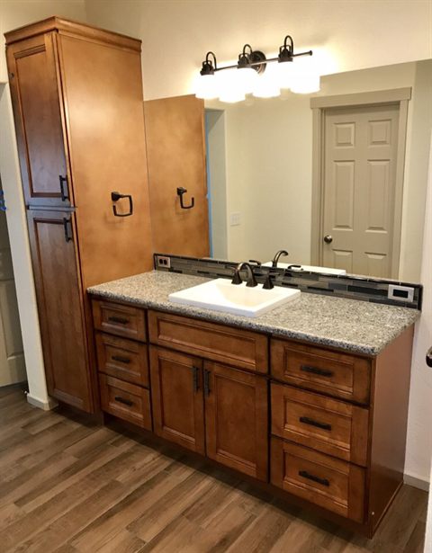 Custom stained wood bathroom vanity with a granite top and a matching framed mirror