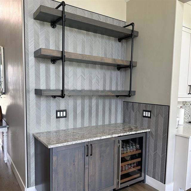 Custom dry bar with industrial bracket floating shelves, wine fridge and granite counter
