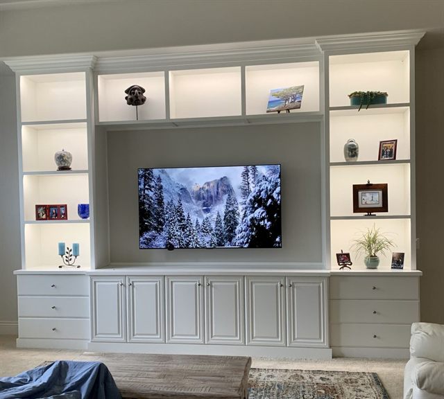 Built-in entertainment center with a television niche, lit display cubbies and drawer bases