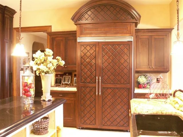 Custom refrigerator surround in stained wood with a domed arched top and lattice panel doors