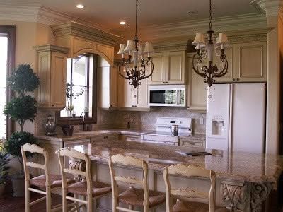 Traditional glazed maple kitchen with a granite-topped island and two chandeliers above it